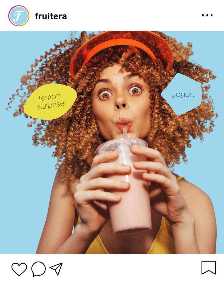 A woman with curly hair holds a drink, looking cheerful.