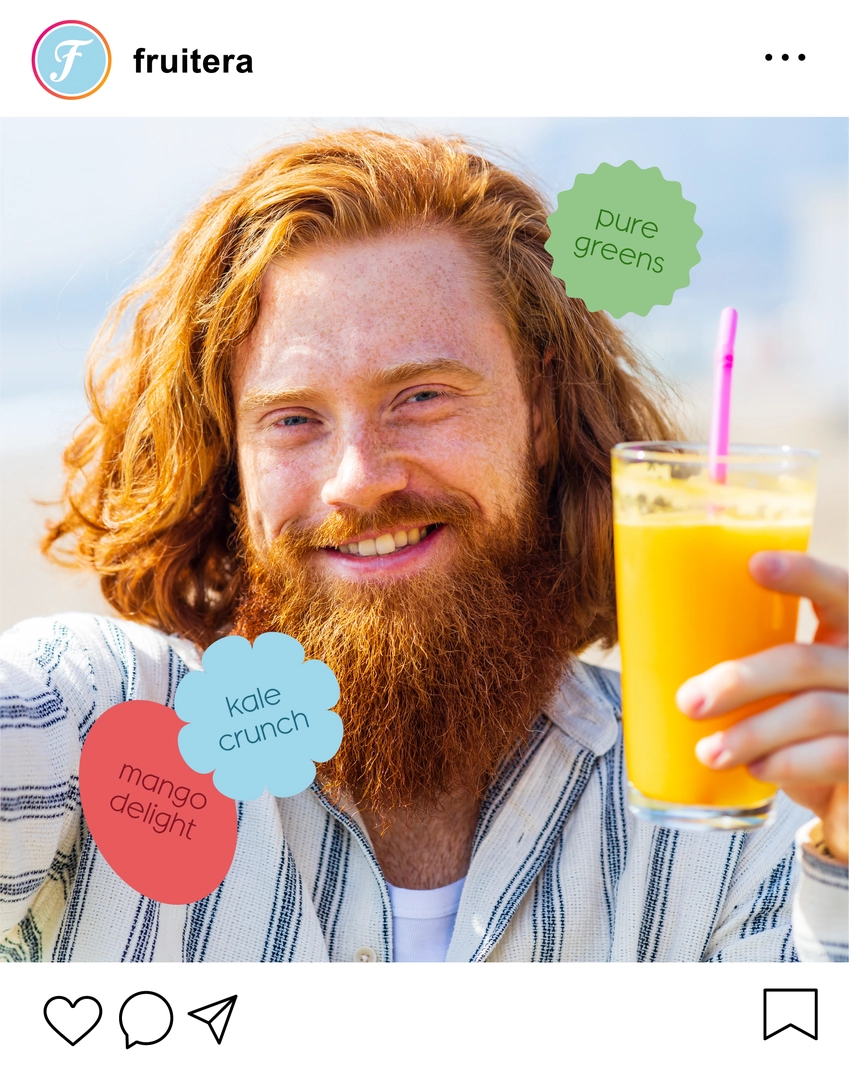 A bearded man with long hair smiles while holding up a glass of smoothie, showcasing a refreshing drink.