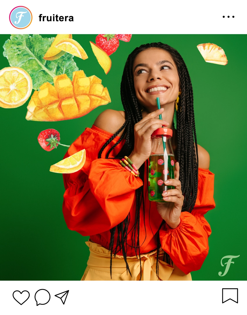 A woman smiles while holding a colorful drink garnished with fresh fruit.