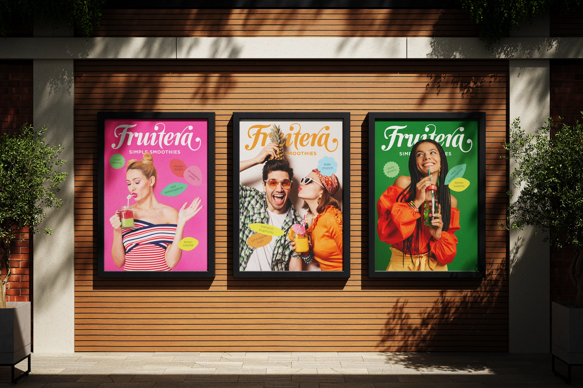 Three colorful posters hang on a wall, with a green plant softly blurred in the background.